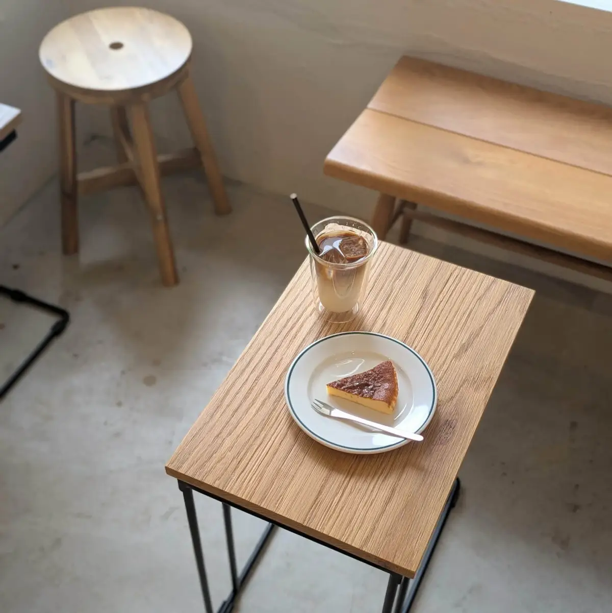 木のテーブルに置かれたアイスカフェラテとバスクチーズケーキ